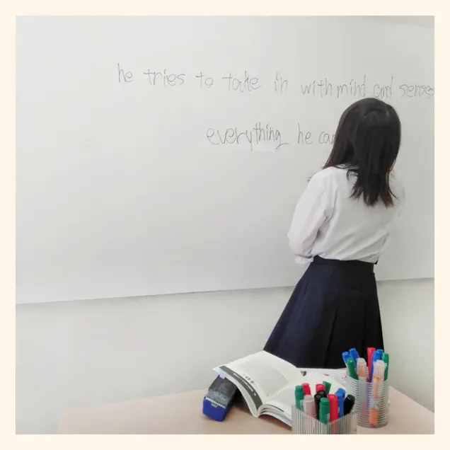 生徒がホワイトボードに英文を書いて先生に説明している様子