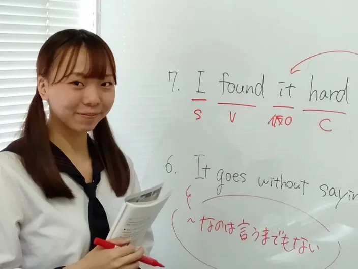 生徒がホワイトボードで英文法を先生に説明している様子