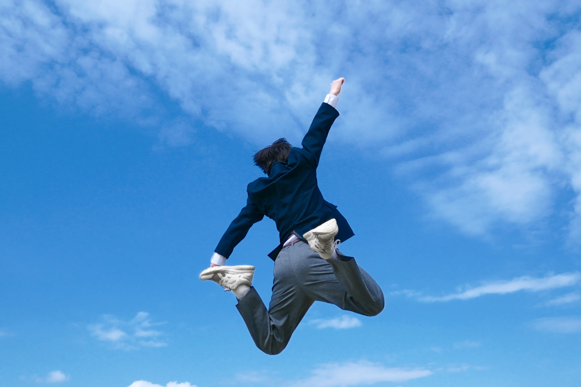 青空に向かってジャンプする男の子