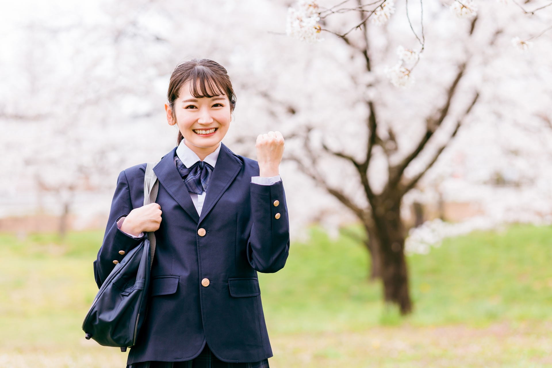 満開の桜の下の高校生（ガッツポーズ）