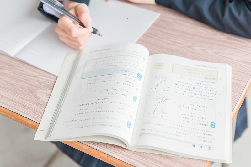 数学の教科書を見ながら勉強する女子高校生