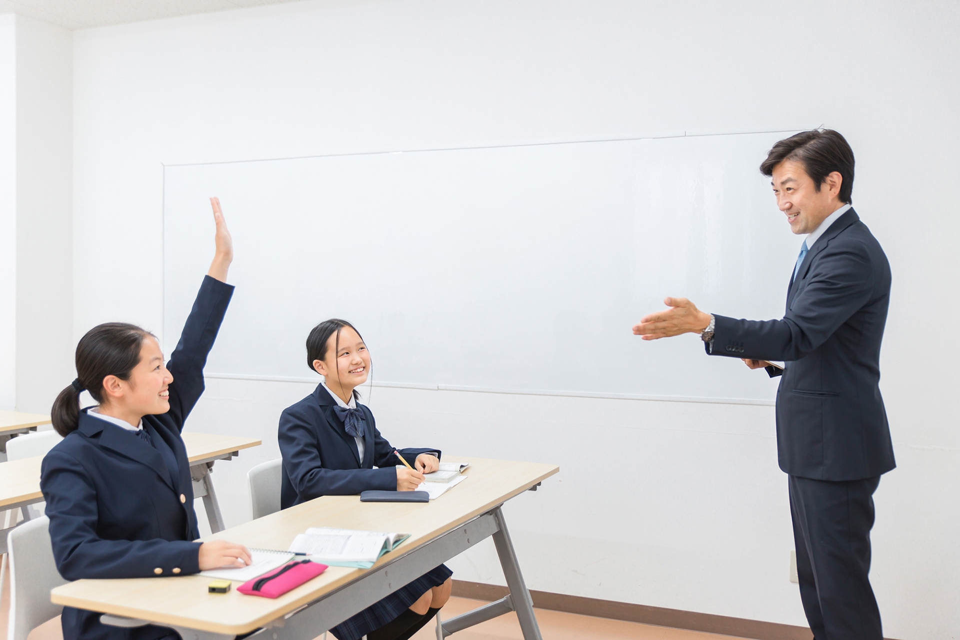 塾で先生に勉強を教わる中学生・高校生