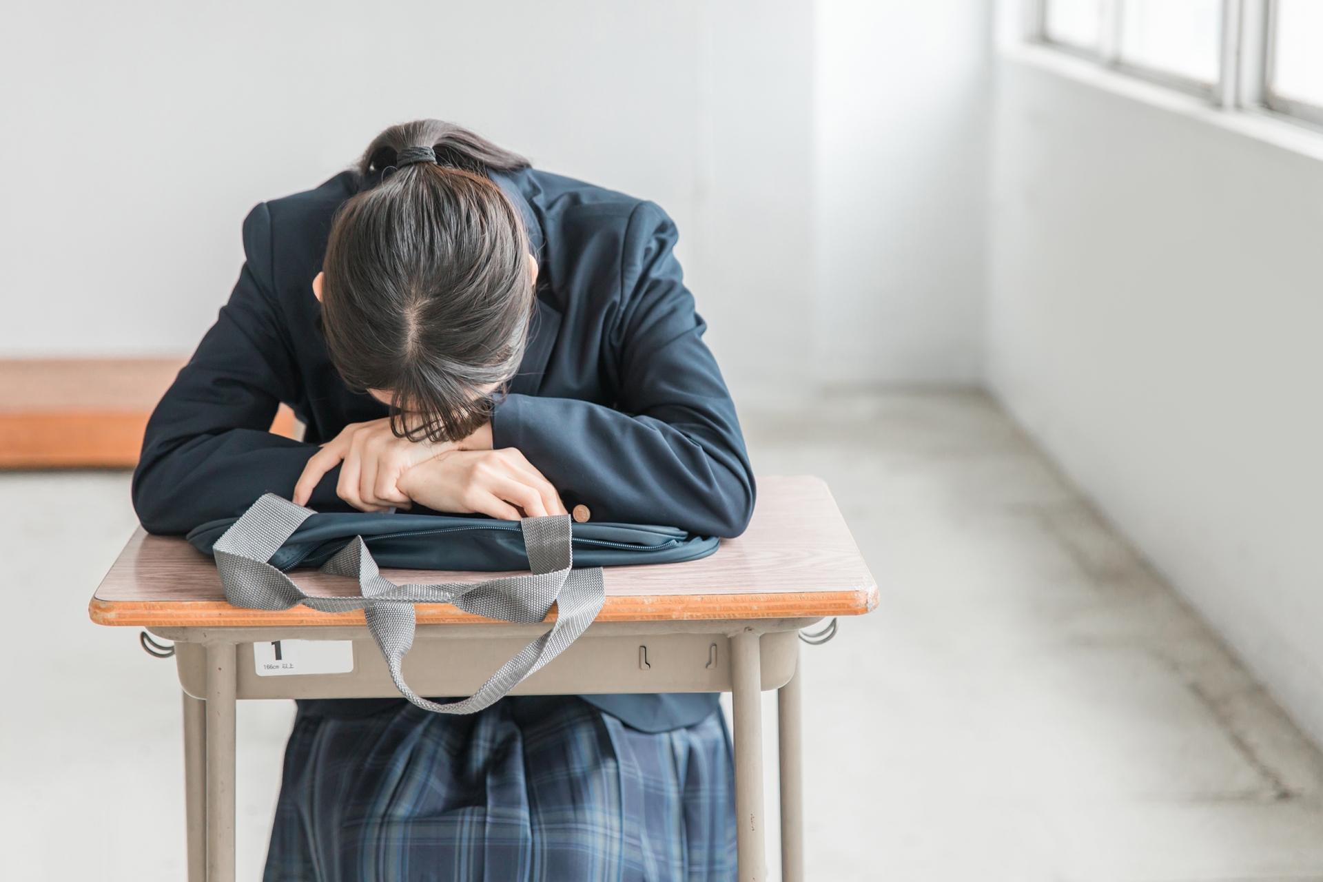 学校の教室で落ち込む女子高校生・中学生