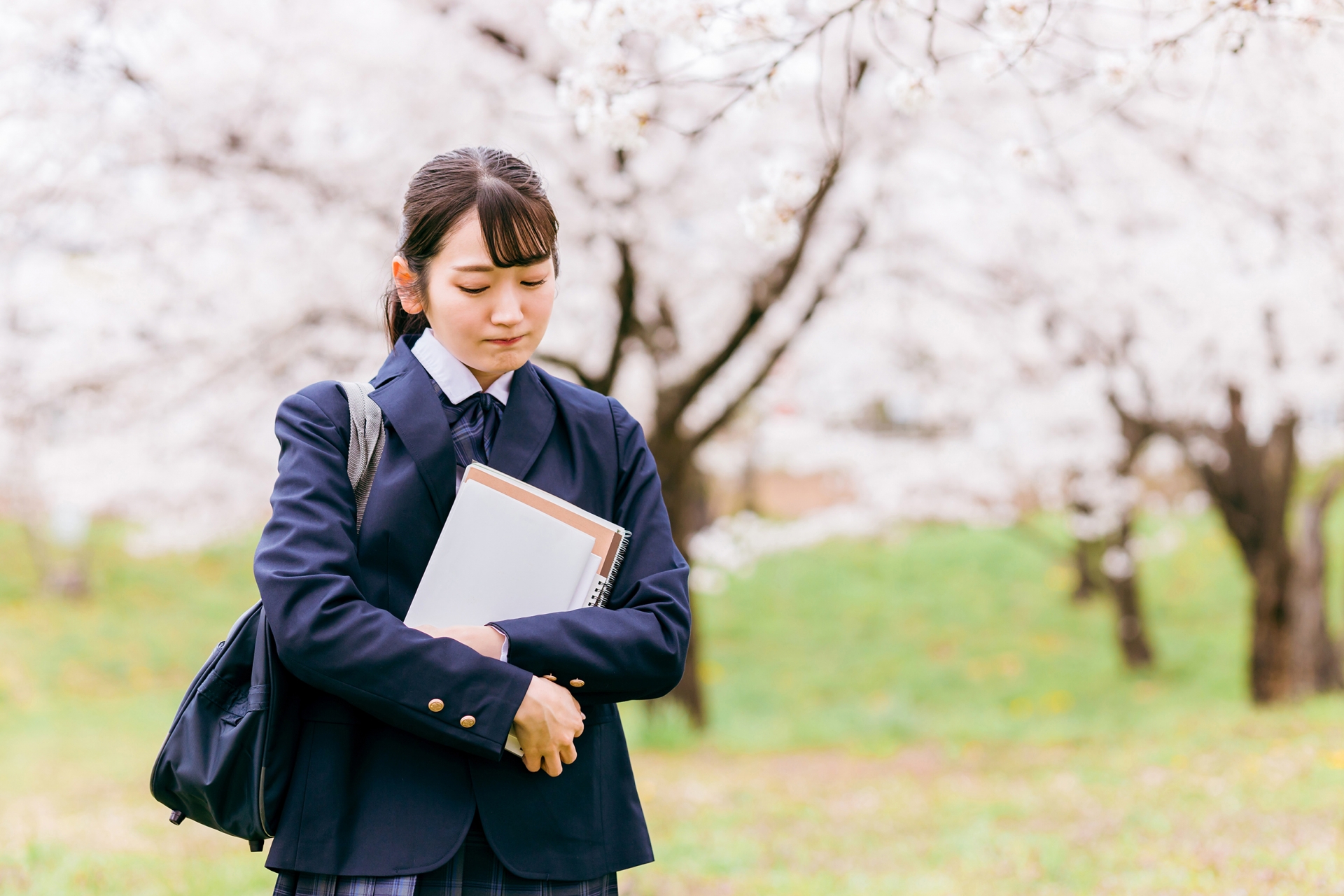 桜の中を歩く落ち込む・悩む高校生