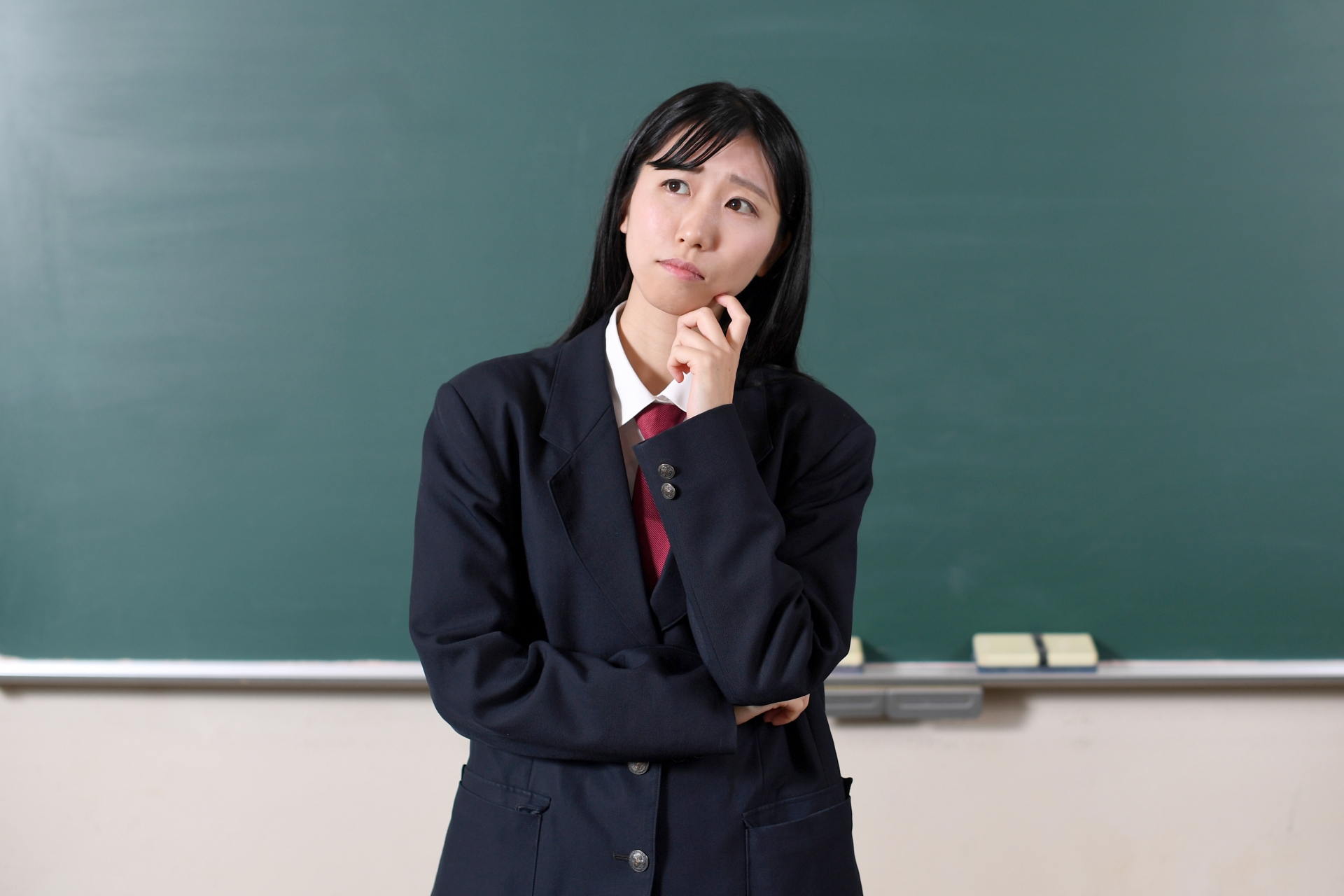 黒板の前で悩む制服を着た女子学生