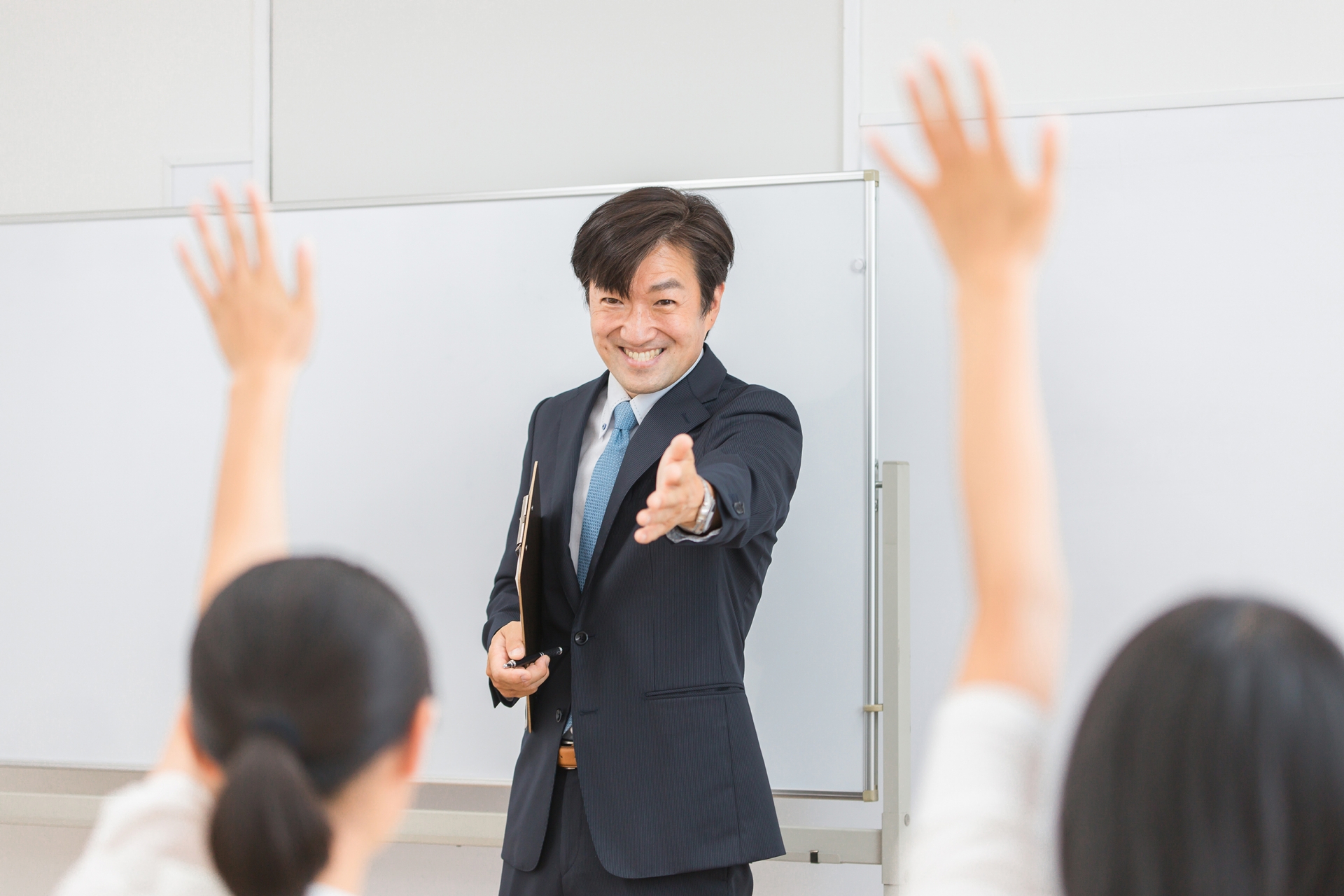 笑顔で教える先生と挙手する人