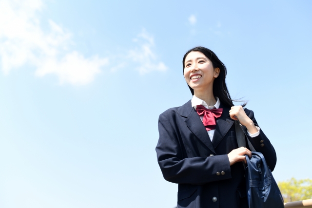 屋外にいるブレザー姿の女子学生