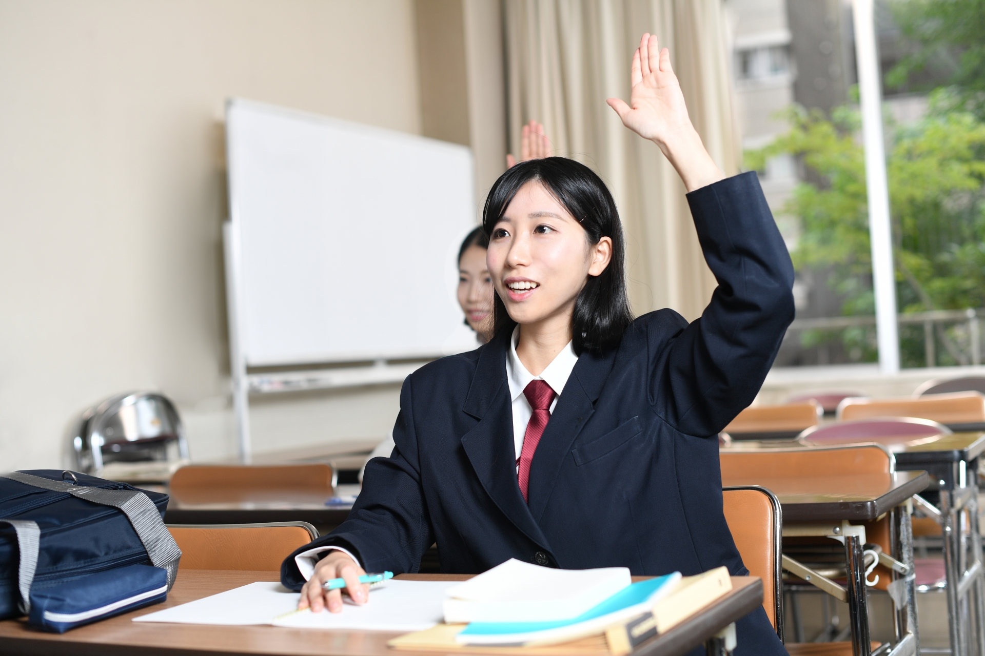 授業中に手を挙げる女子学生のイメージ