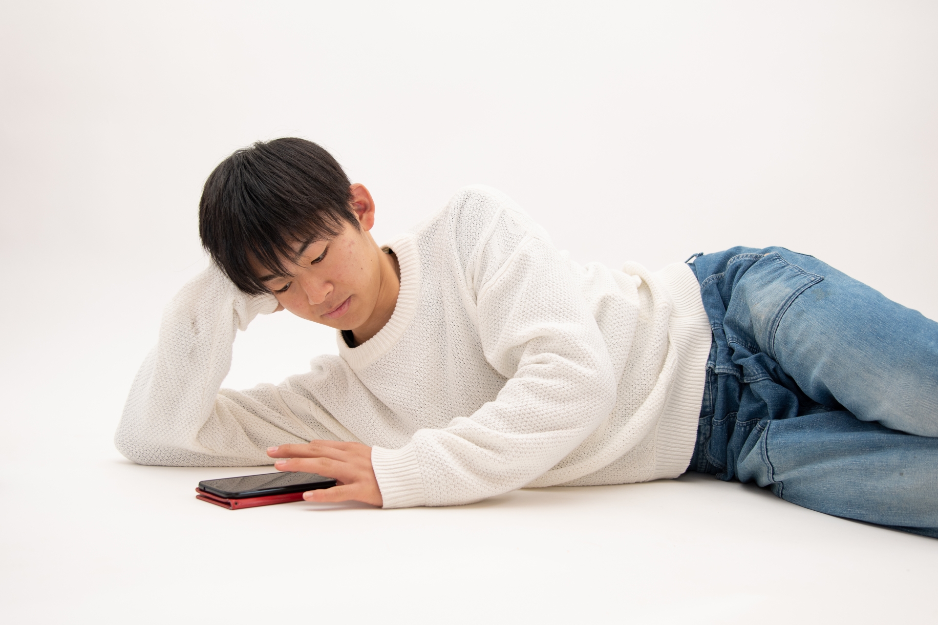 スマートフォンを見ながらくつろぐ男子高校生