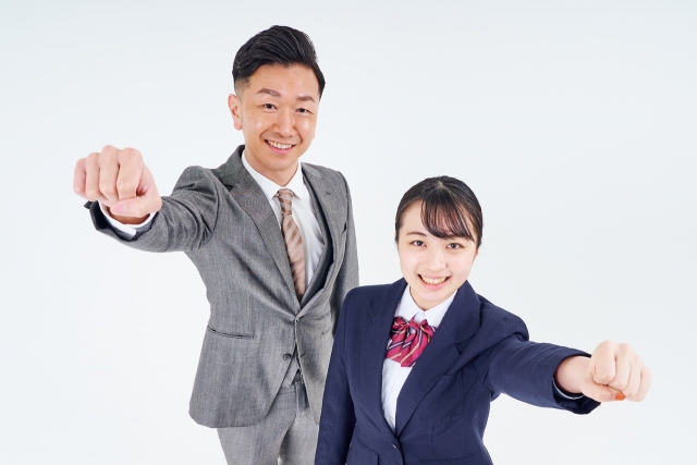 ガッツポーズするスーツ姿の男性と女子高生