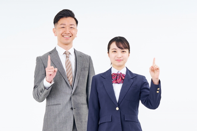 人差し指を立てるスーツ姿の男性と女子高生