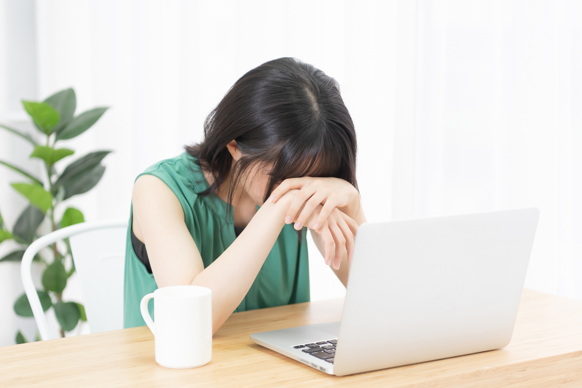 ノートパソコンの前で落ち込んでいる女性