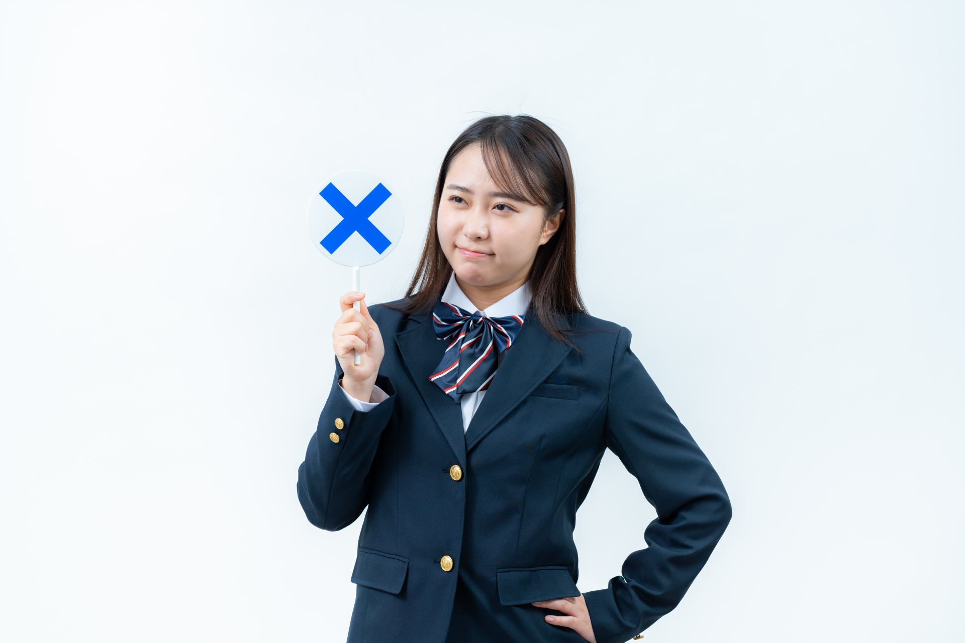 バツ印のプレートを持つ女子高校生