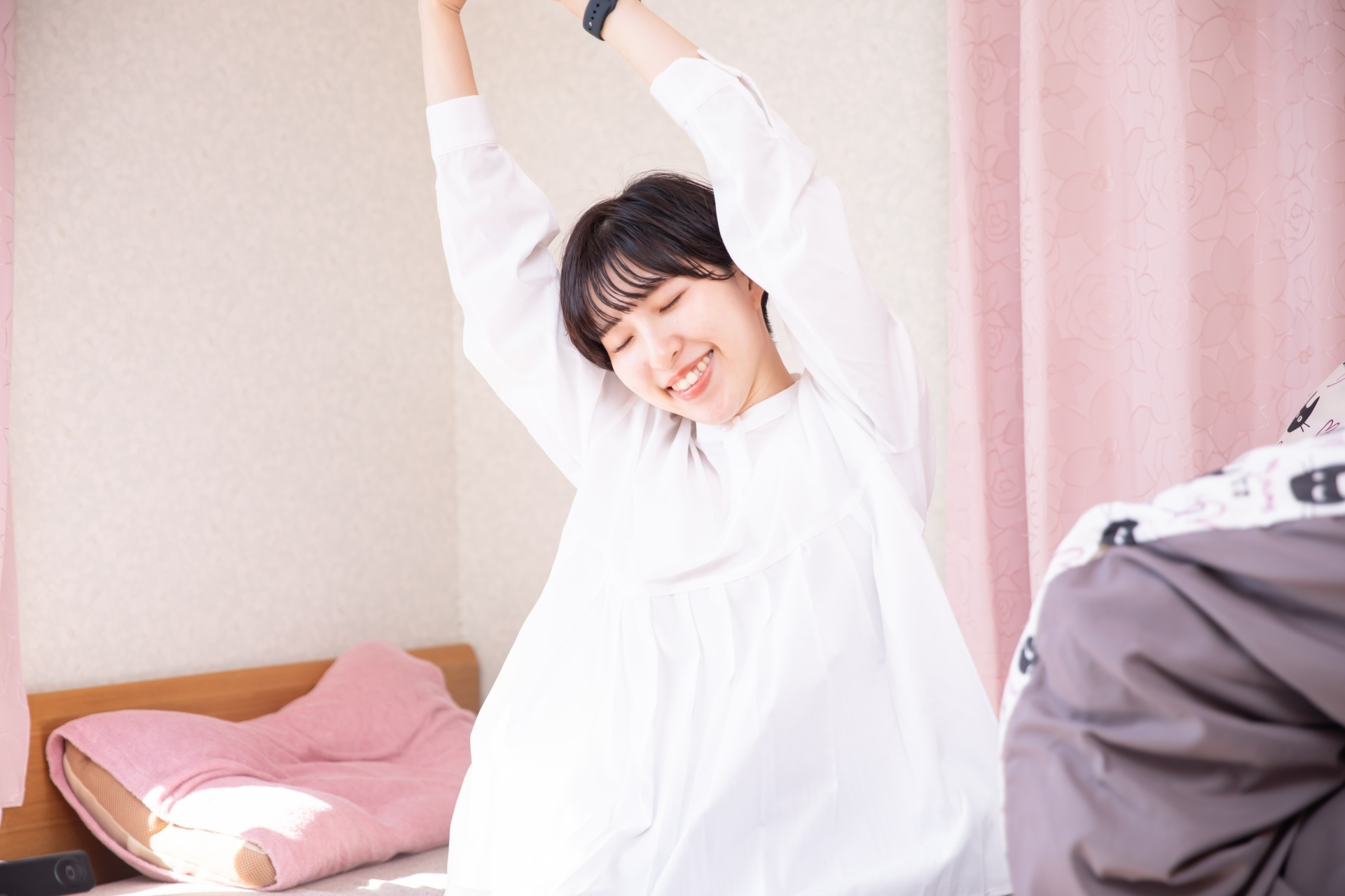 ベッドで背伸びする女性