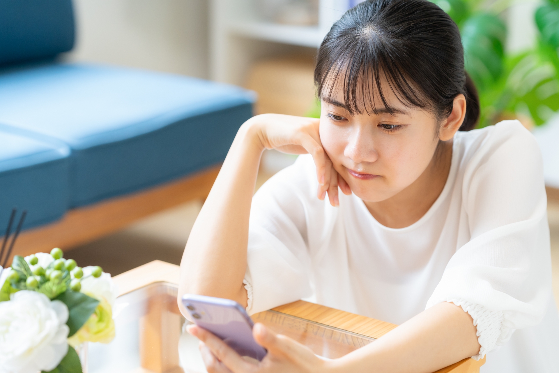 リビングでスマホを見る大学生の女性