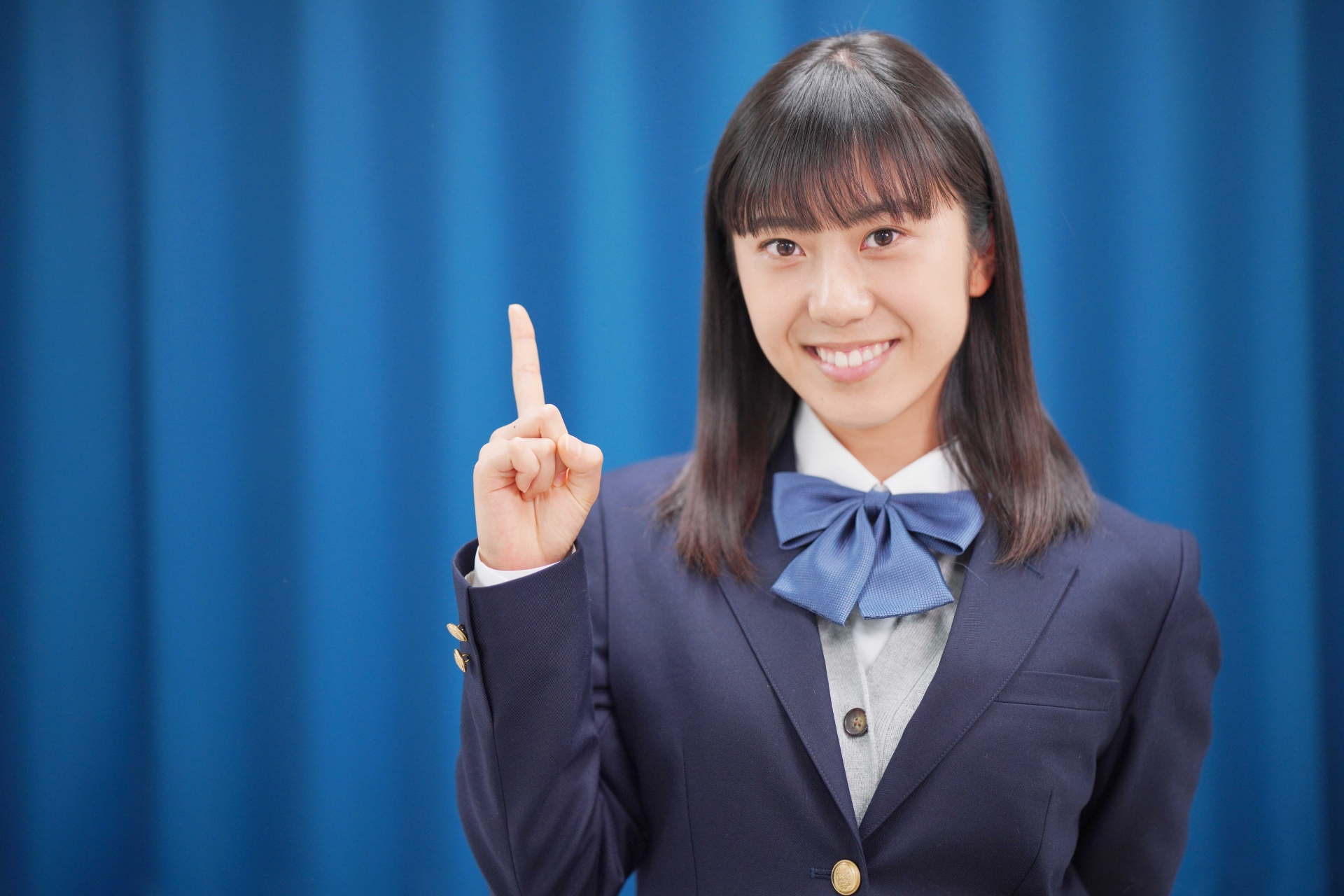 人差し指を立てる女子高生