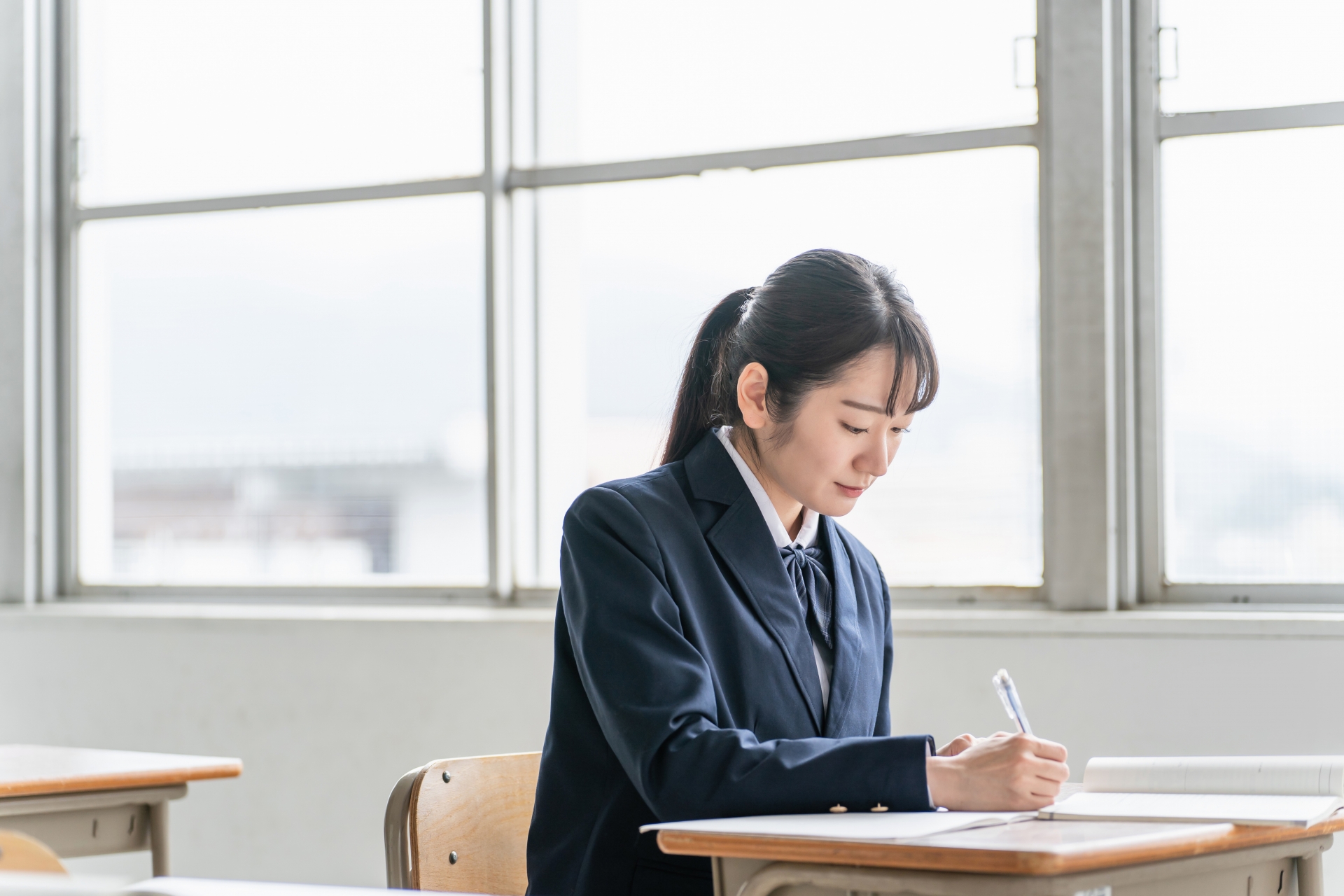 教室で参考書を見ながら勉強する女子高校生