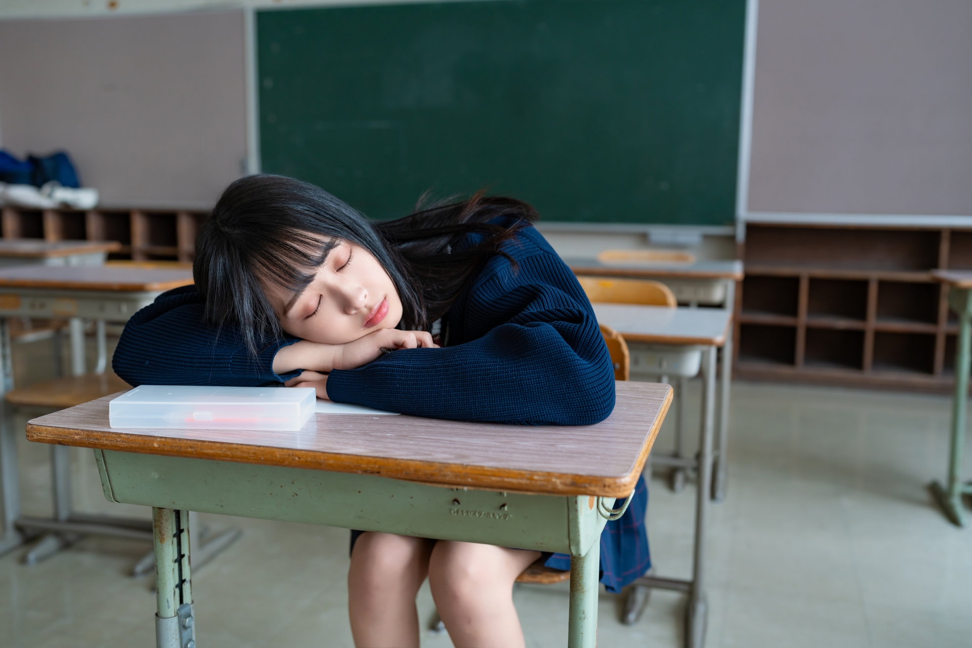 勉強に疲れて机で寝る女子高校生