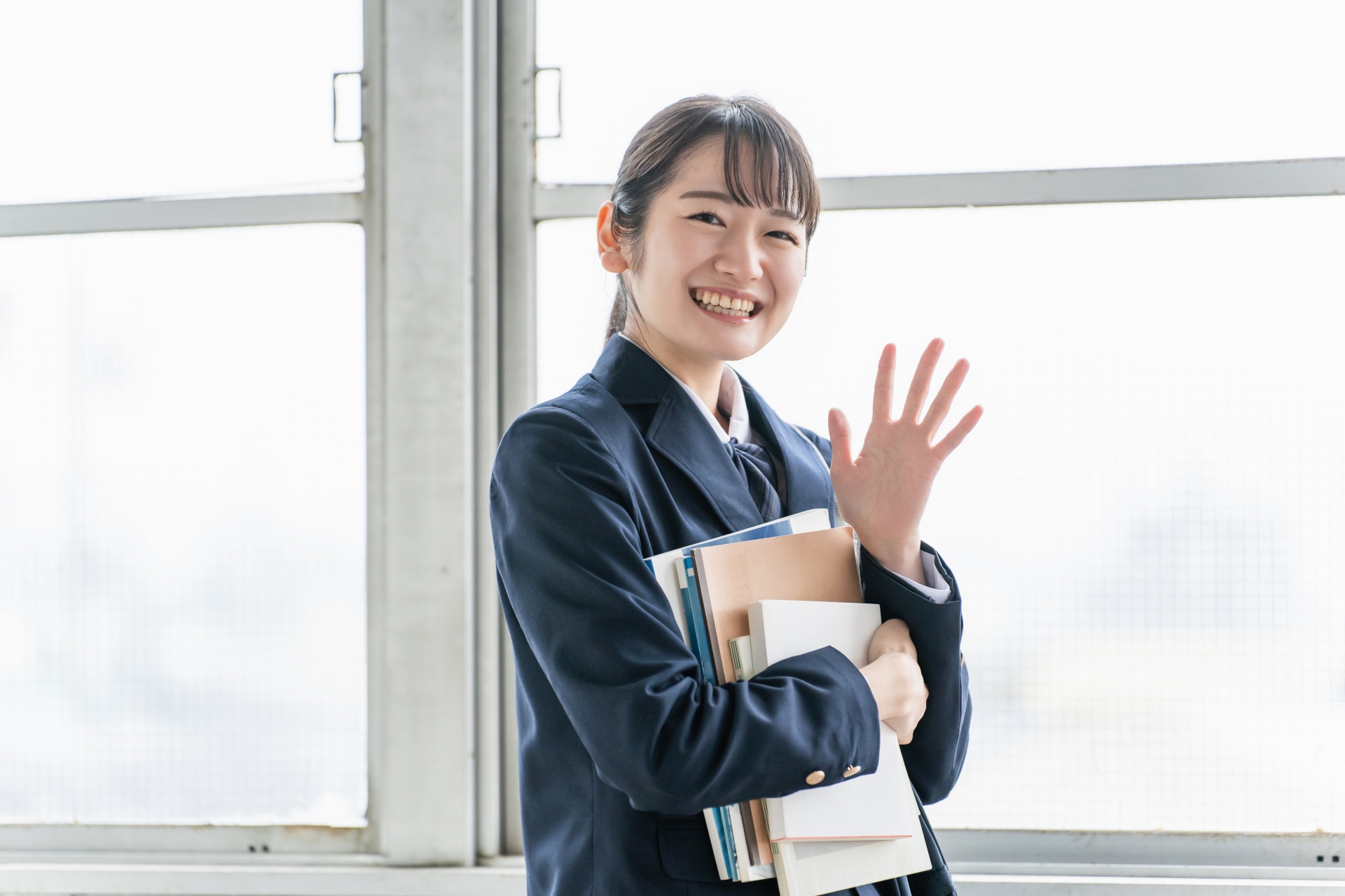 学校の教室で友達に手を振る女子高生