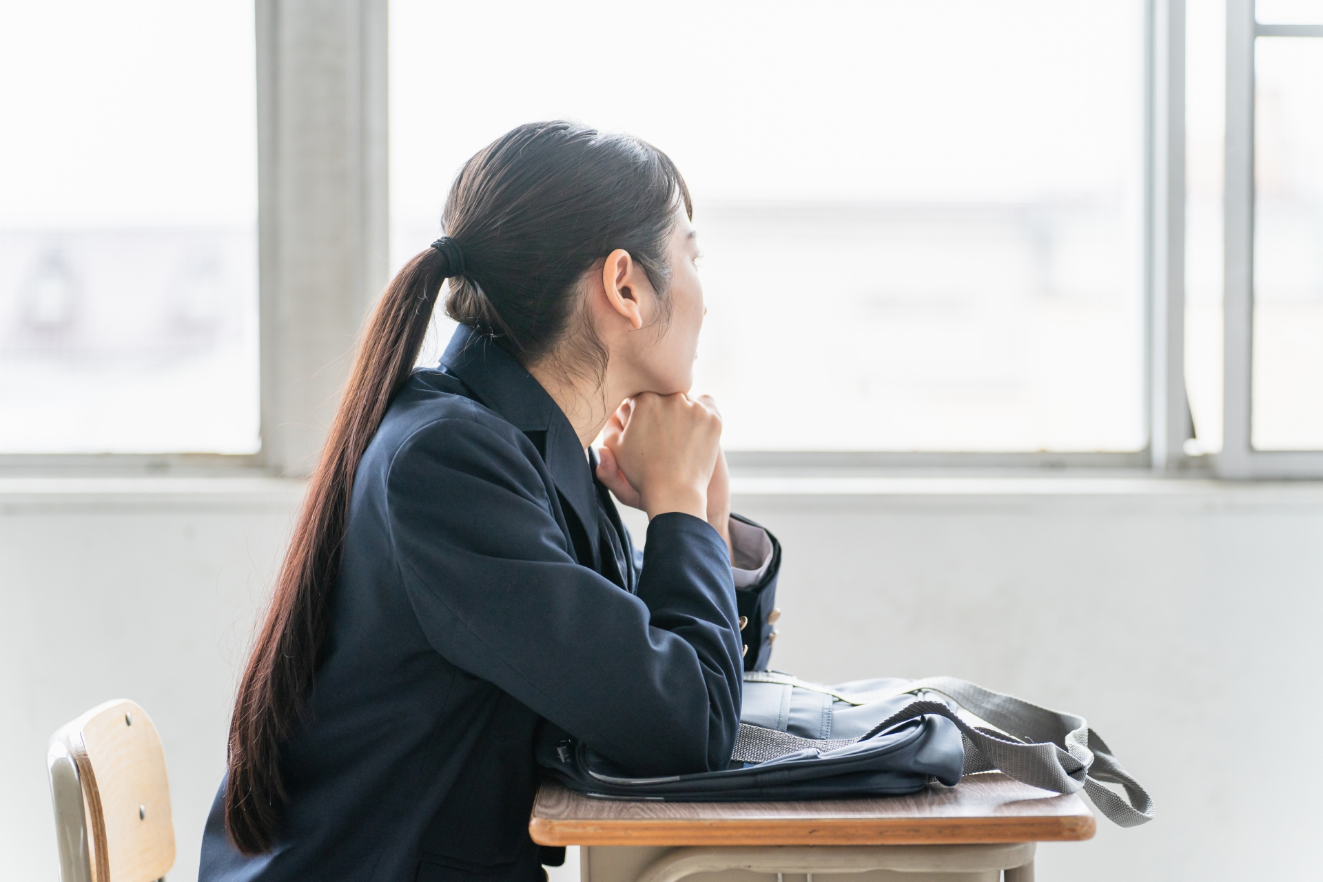 学校の教室で悩んでいる女子高校生・思春期