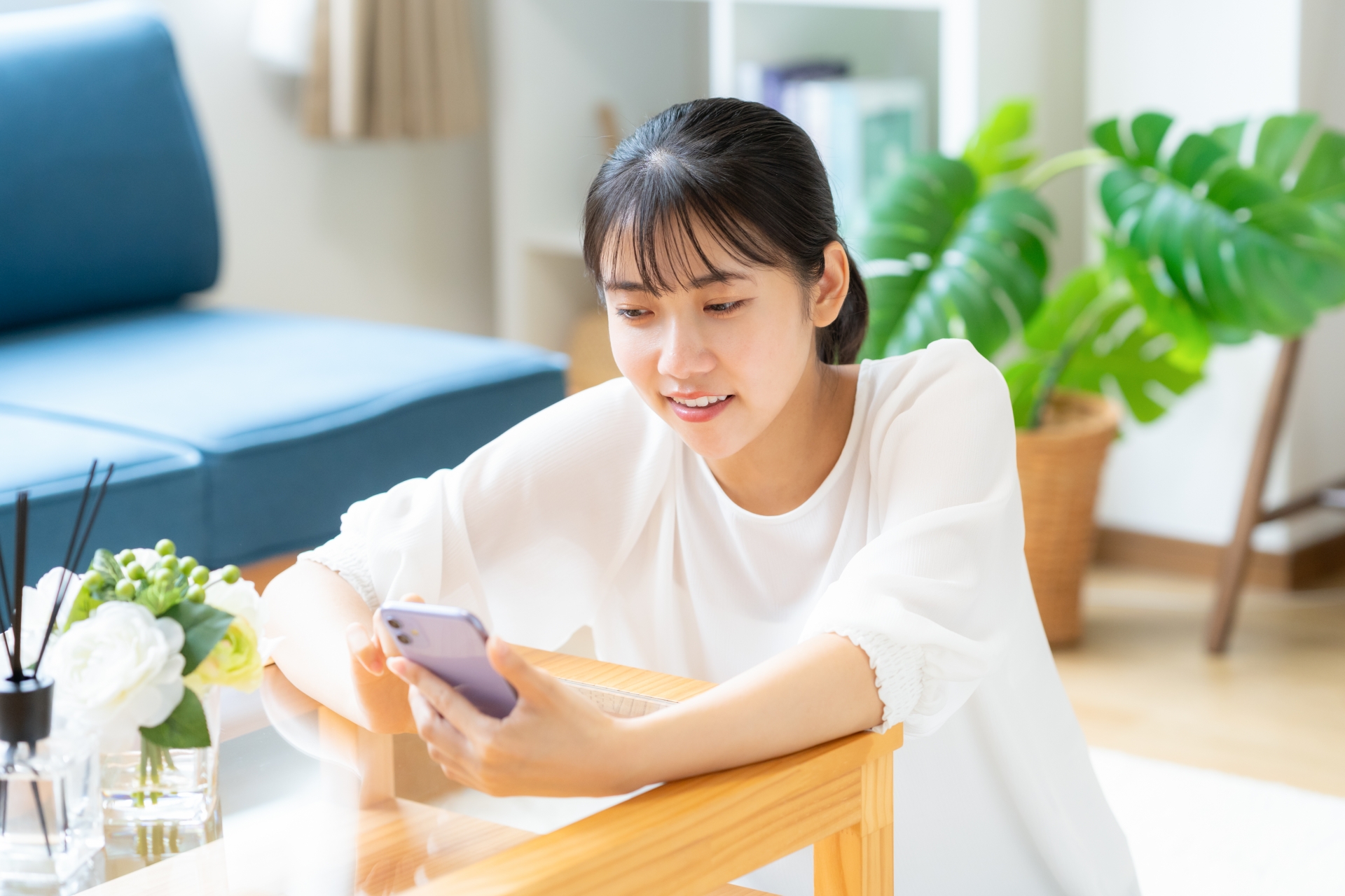 リビングでスマホを見る大学生の女性