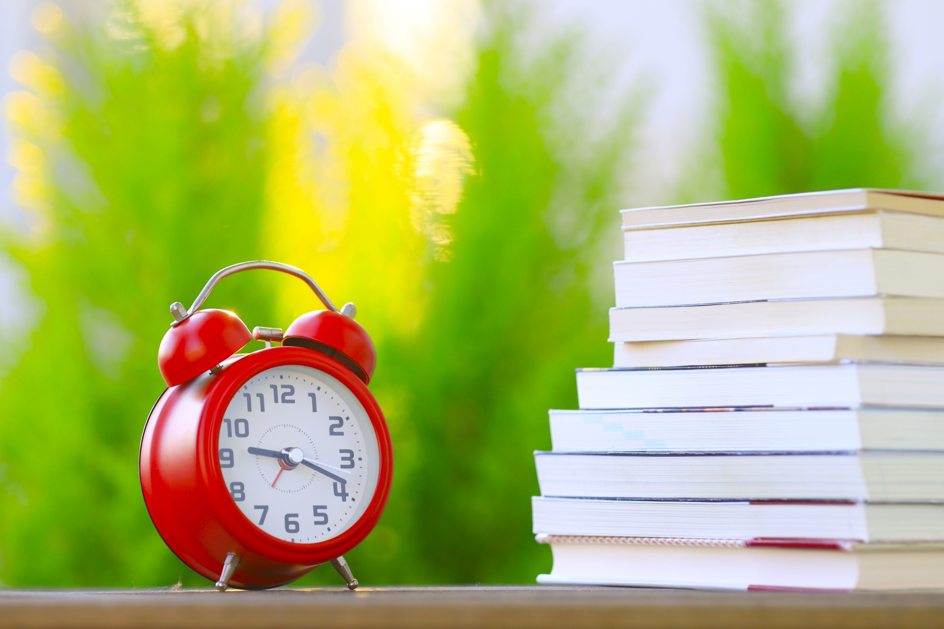 時計と積み重なった本 緑ぼかし背景