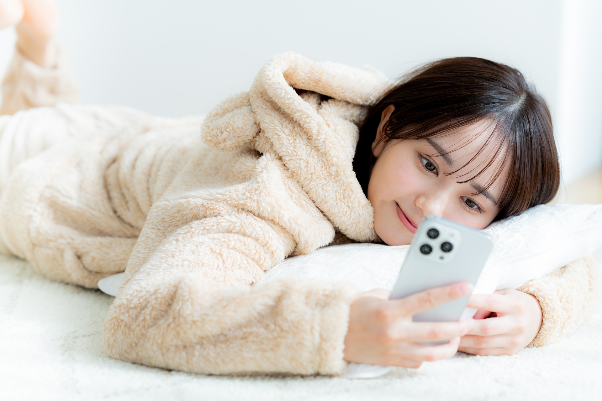 部屋でスマホを操作する若い女性