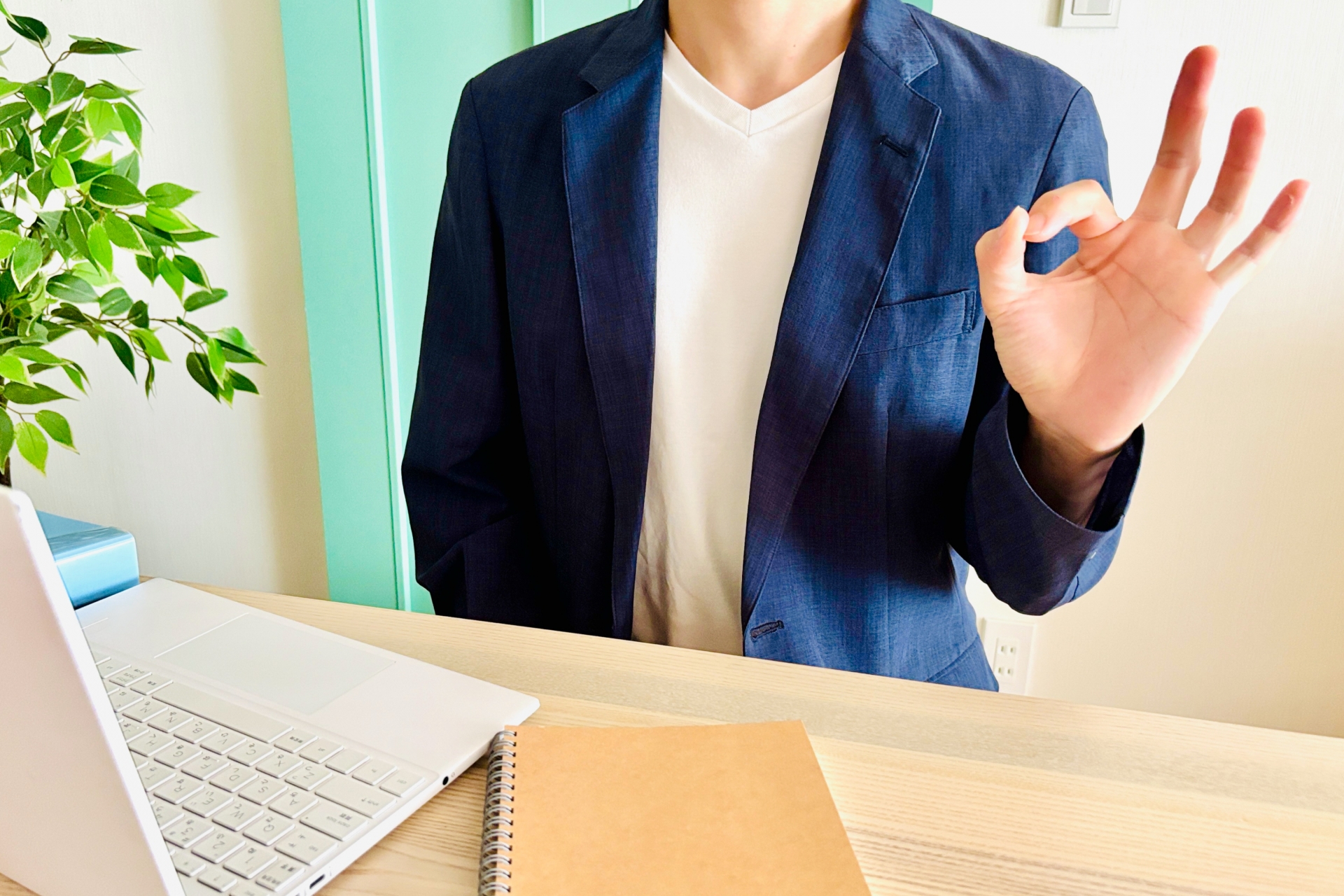 室内でOKのポーズをする座った男性