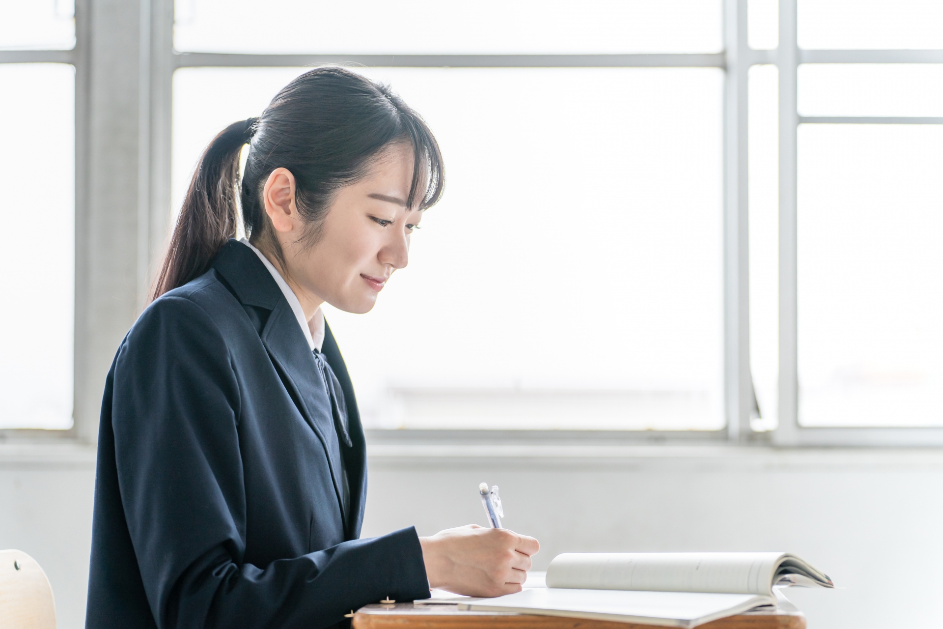 教室で教科書を見ながら勉強する女子高校生