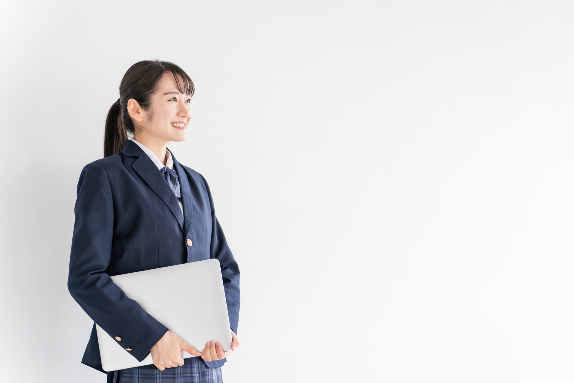 学校の教室でノートパソコンを持つ高校生